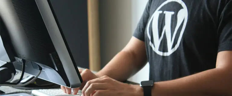 Ein Mann am Computer mit WordPress Logo auf dem T-Shirt