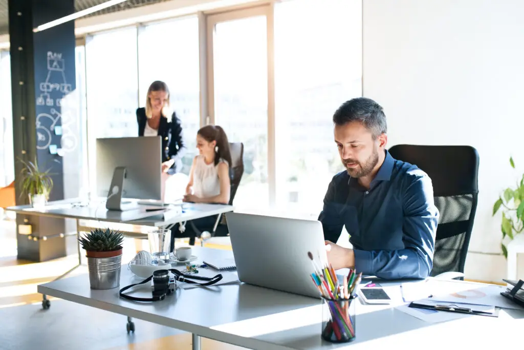 WordPress für Unternehmen: Team im modernen Büro arbeitet gemeinsam am Laptop und nutzt das CMS für digitale Projekte im Mittelstand.
