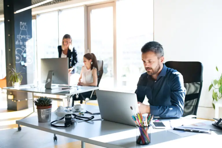 WordPress für Unternehmen: Team im modernen Büro arbeitet gemeinsam am Laptop und nutzt das CMS für digitale Projekte im Mittelstand.