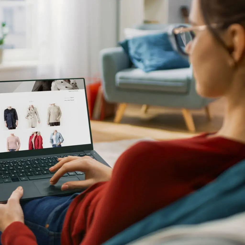 Person sitzt auf dem Sofa und schaut sich Produkte in einem WooCommerce Online Shop auf dem Laptop an