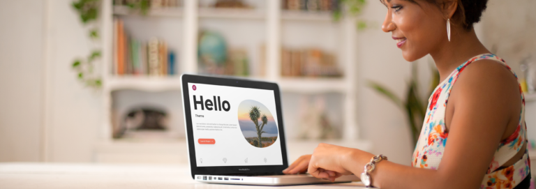 Frau arbeitet zu Hause an einem MacBook mit geöffneter Hello-Theme-Seite von Elementor